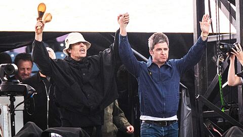 Liam und Noel Gallagher triumphierend auf der Bühne.