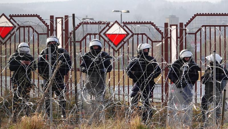 Polnische Sicherheitskräfte stehen an der Grenze hinter Stacheldraht.