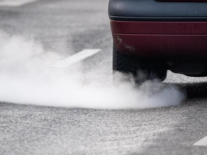 Ein Auto stößt Abgase aus. Die neue CO2-Regelung wird nicht so streng wie ursprünglich geplant.