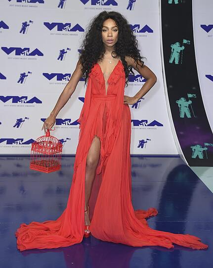Top: Lil Mama mit einem roten Walle-Kleid mit Schlitz und einem Vogelkäfig als Accessoire