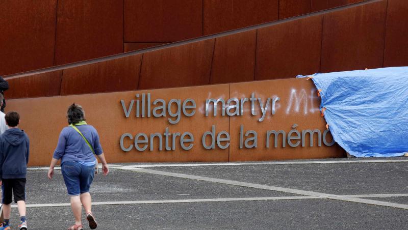 Besucher gehen an einem abgedeckten Graffiti auf dem Schriftzug am Eingang der Gedenkstätte in Oradour-sur-Glane vorbei. Unbekannte hatten unter anderem das Wort "Märtyrer" im Schriftzug mit weißer Farbe durchgestrichen und "Lügner" daneben geschrieben. Besucher gehen an einem abgedeckten Graffiti auf dem Schriftzug am Eingang der Gedenkstätte in Oradour-sur-Glane vorbei. Unbekannte hatten unter anderem das Wort "Märtyrer" im Schriftzug mit weißer Farbe durchgestrichen und "Lügner" daneben geschrieben.