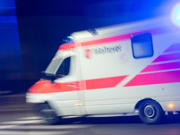 Ein Rettungswagen der Malteser fährt mit Blaulicht durch die Nacht. Foto: Patrick Seeger/Archiv
