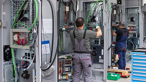 Mitarbeiter verdrahten Ladesysteme von Siemens für Elektroautos.