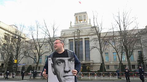 Ein Aktivist steht mit einem Plakat von Kremlkritiker Alexej Nawalny vor der russischen Botschaft in Berlin und protestiert.