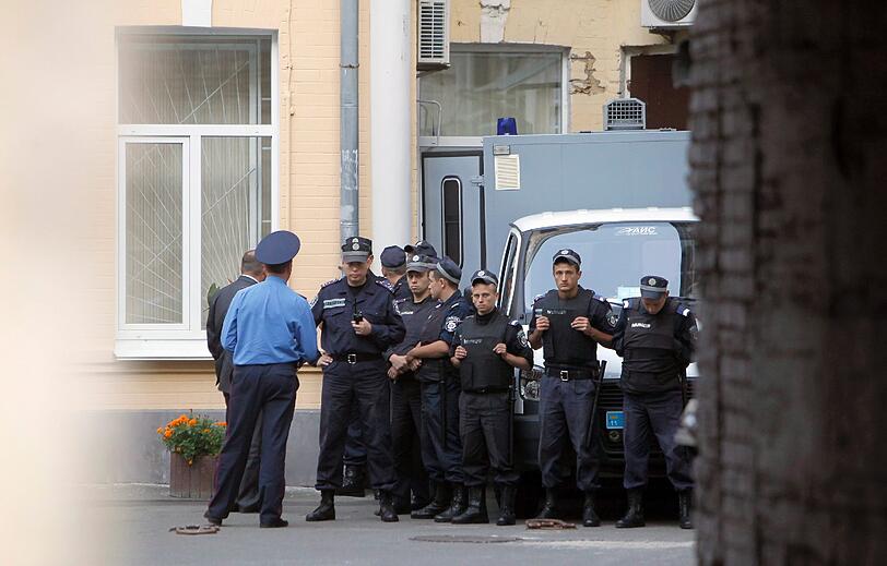 Die Ex-Premierministerin wird zum Gericht gebracht. Polizisten schützen den Wagen vor der tobenden Menge.
