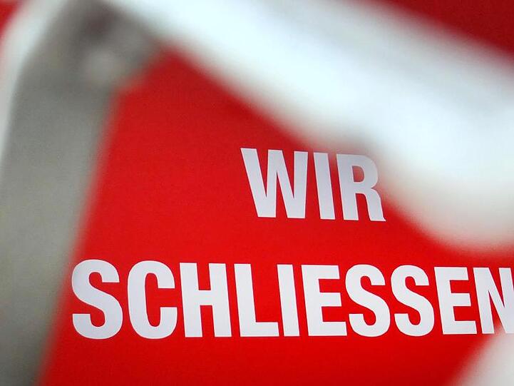 Der Schriftzug "Wir schließen!" steht hinter einem Rollgitter an einem geschlossenen Geschäft.