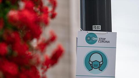 Ein Schild, mit dem auf die Maskenpflicht hingewiesen wird, hängt an einer Laterne.