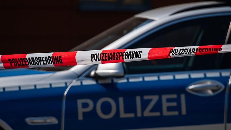 Ein Polizeiauto steht hinter einem Absperrband.
