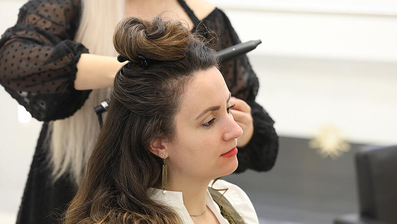 Die Haare an der Hutlinie teilen. Den oberen Haarteil zu einem Knoten drehen und mit einer Klammer befestigen.