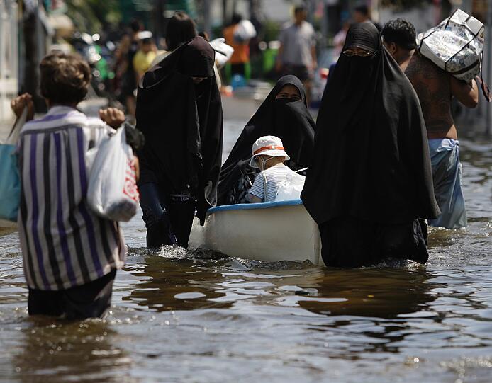 Mit Hilfe von Booten schaffen Flüchtlinge das Wichtigste aus der überfluteten Stadt.