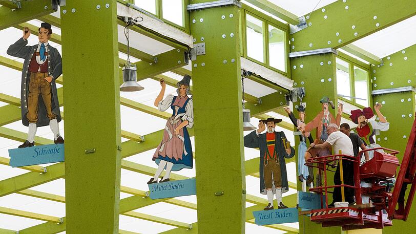 Arbeiter montieren verschiedene Trachtenfiguren an den Dachträgern.