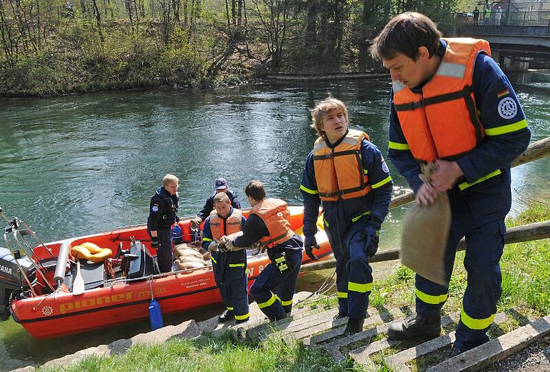 Helfer des THW München verladen am Samstag in München während einer Großübung Sandsäcke in ein Motorboot.