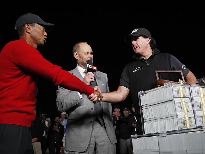 Neben einem Haufen Banknoten reicht Sieger Phil Mickelson (r) Tiger Woods (l) die Hand.