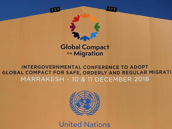 Die Logos der Vereinten Nationen und des Migrationspakts an einem Gebäude in Marrakesch.