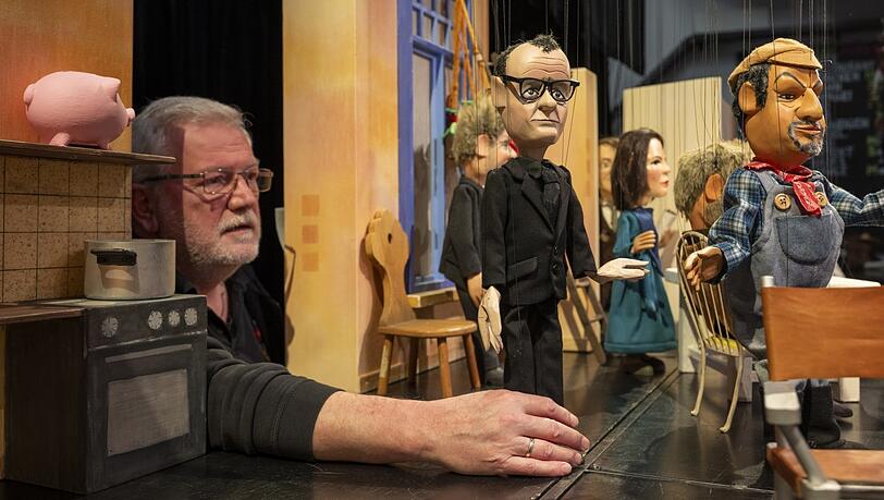 Theaterleiter Klaus Marschall rückt in der Augsburger Puppenkiste die Marionette von Friedrich Merz (CDU) in die Szene des Kabarettstücks "Das Ende der Ampel-WG". Die Puppenkiste bietet nicht nur Programm für Kinder.