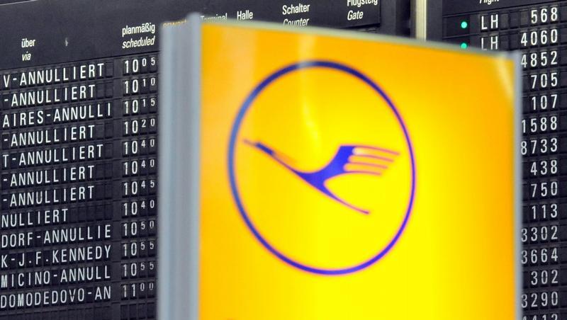 Ein Lufthansa-Logo vor einer Anzeigetafel, auf der zahlreiche Flüge annulliert sind. Ein Lufthansa-Logo vor einer Anzeigetafel, auf der zahlreiche Flüge annulliert sind.