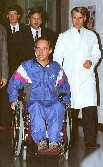 Wolfgang Schäuble (CDU) fährt knapp sechs Wochen nach dem Attentat in der Reha-Klinik Langensteinbach mit dem Rollstuhl zu einer Pressekonferenz, rechts steht Professor Jürgen Harms. (Archivfoto vom 22.11.1990)