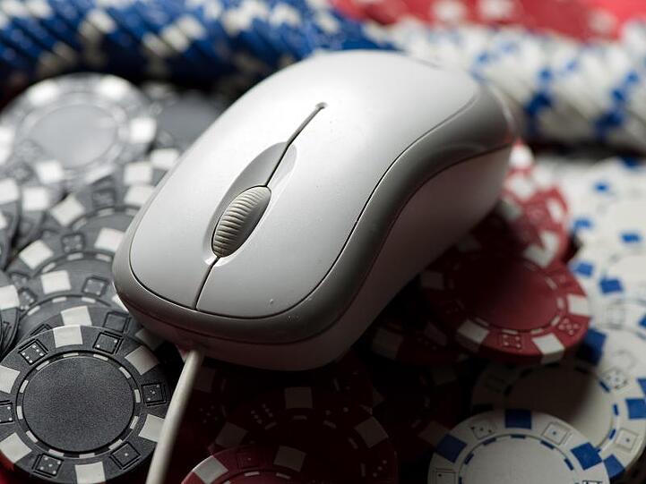 Eine Computermaus liegt auf einem Stapel Glücksspiel-Jetons.