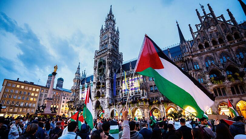 Ein Mann schwenkt während einer Kundgebung für Palästina auf dem Marienplatz eine palästinische Flagge.