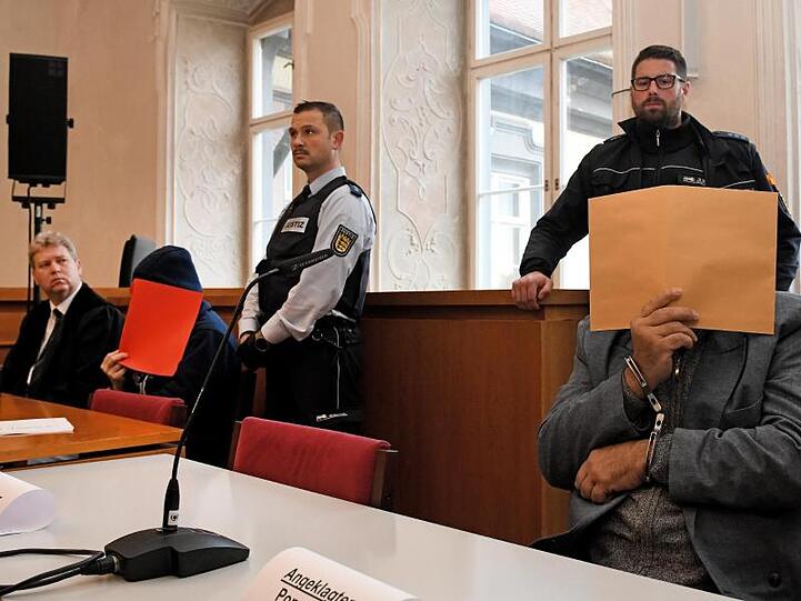 Der angeklagte Vater (r) auf der Anklagebank, links Verteidiger Stephan Bauer mit einem der Söhne. Foto: Stefan Puchner/dpa/Archivbild