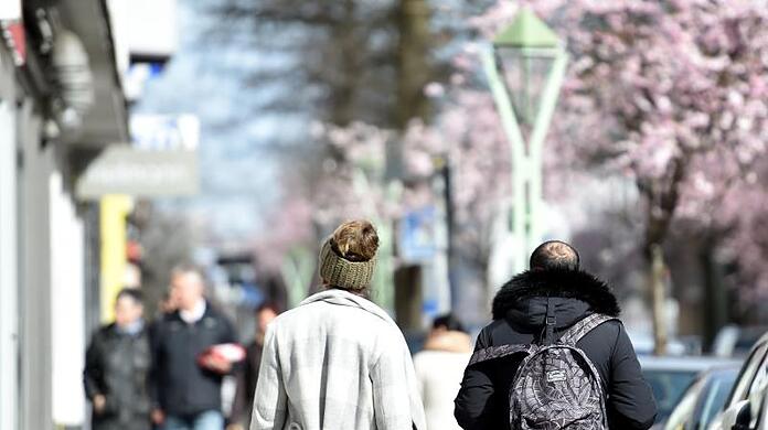 Menschen spazieren in Essen und genießen das sonnige Wetter.