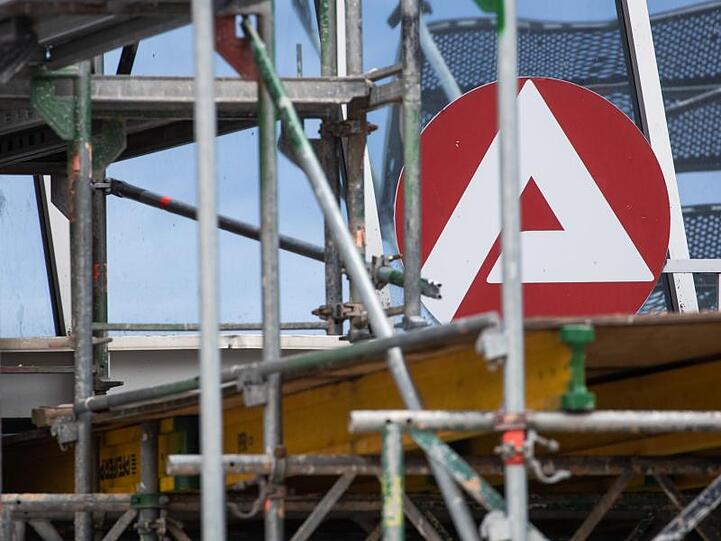 Das Logo der Agentur für Arbeit befindet sich an einer Niederlassung in der Innenstadt hinter einem Baugerüst. Foto: Daniel Karmann/Archiv
