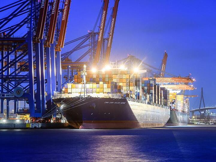 Das Containerschiff "CMA CGM Jules Verne" liegt in der Abenddämmerung am Containerterminal Burchardkai in Hamburg.