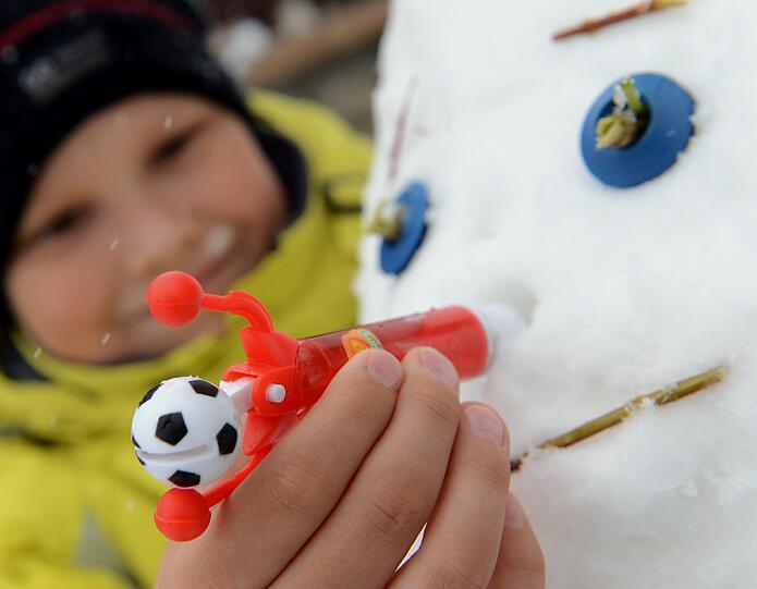 Der neunjährige Jonas steckt seinem Schneemann stolz die rote Nase auf. Im thüringischen Weimar hat es heute Nacht zum ersten mal geschneit.