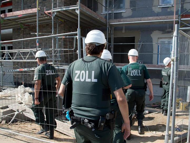 Zollbeamte betreten bei einer Razzia gegen Schwarzarbeit eine Baustelle.