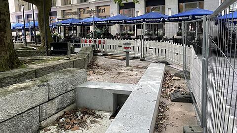 In den neu angelegten Brunnenbecken liegt altes Laub. Ein Bauzaun sperrt den Bereich vor dem Klosterwirt ab.
