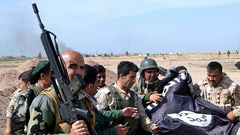 Kurdische Kämpfer präsentieren eine erbeutete Flagge der Terrormiliz IS. Kurdische Kämpfer präsentieren eine erbeutete Flagge der Terrormiliz IS.