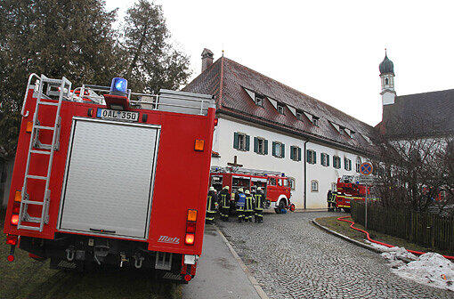 Einsatzkräfte der Feuerwehr stehen am Sonntagmorgen vor dem Franziskanerkloster in Füssen.