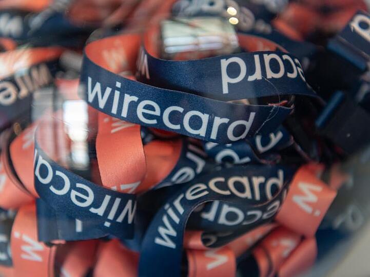 Umhängebändchen mit der Aufschrift "wirecard" liegen in einem Glasbehälter. Foto: Peter Kneffel/dpa/Archivbild