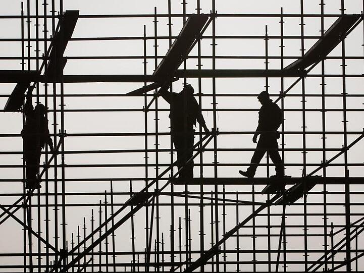 Gerüstbauer errichten in Hamburg auf einer Brückenbaustelle in der Hafencity ein Gerüst.