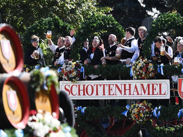Gäste feiern beim Einzug der Wiesn-Wirte zum Oktoberfest auf einer Kutsche. Foto: Angelika Warmuth