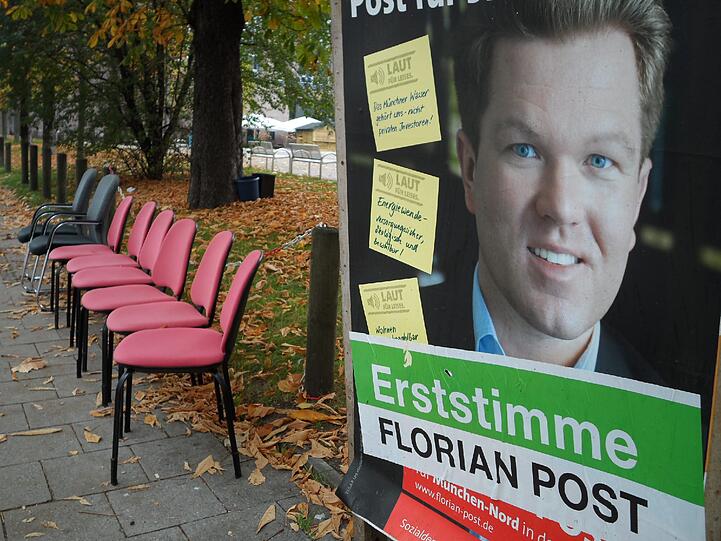 Zwei schwarz-graue uns sechs rote Stühle stehen am Rundfunkplatz aufgereiht. Dazu noch ein bisschen Geschirr. Und ein längst überfälliges Wahlplakat...