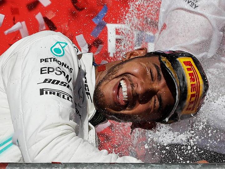 Lewis Hamilton genießt nach seinem sechsten WM-Titel die Champagnerdusche.