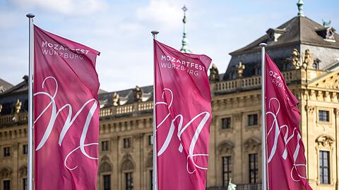 Fahnen mit der Aufschrift "Mozartfest Würzburg" wehen vor der Würzburger Residenz.