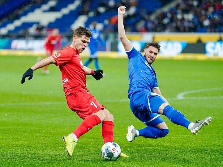 Augsburgs Florian Niederlechner und Hoffenheims Ermin Bicakcic (l-r.) im Zweikampf um den Ball. Foto: Uwe Anspach/dpa
