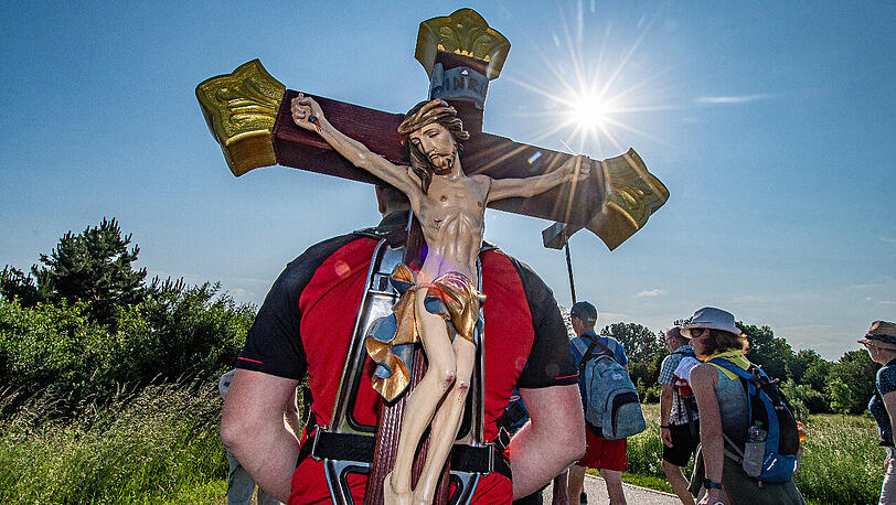 Ein Pilger trägt während der größten Fußwallfahrt Deutschlands ein Holzkreuz.