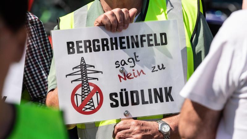 Ein Teilnehmer der Demonstration gegen die geplante Suedlink-Stromtrasse hält ein Transparent mit der Aufschrift "Bergrheinfeld sagt nein zu Südlink" hoch. Foto: Swen Pförtner Ein Teilnehmer der Demonstration gegen die geplante Suedlink-Stromtrasse hält ein Transparent mit der Aufschrift "Bergrheinfeld sagt nein zu Südlink" hoch. Foto: Swen Pförtner