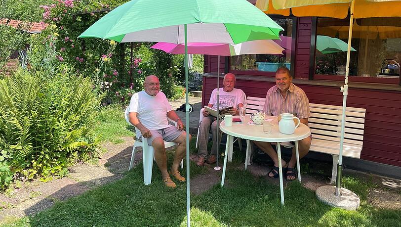 Im Schatten poppiger Sonnenschirme: Karl Beck und Jürgen Spaude beim entspannten Ratsch mit Nachbar Hubert Kühling in der Kleingartenanlage "Villa Flora".