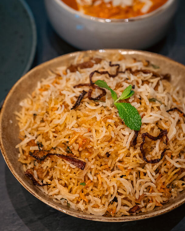 Das Awadhi Dum Biryani gibt es wahlweise mit Huhn oder Lamm und wird mit einem frischen Gurken-Joghurt gegessen.