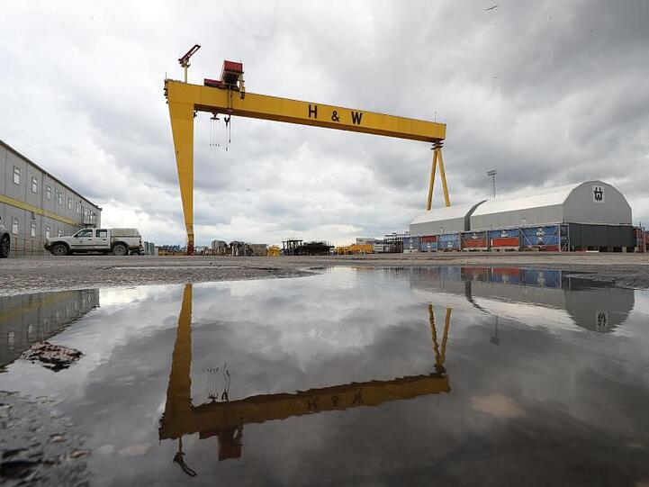 Ein Kran der Werft Harland & Wolff spiegelt sich auf dem Werksgelände in Belfast in einer Wasserlache.