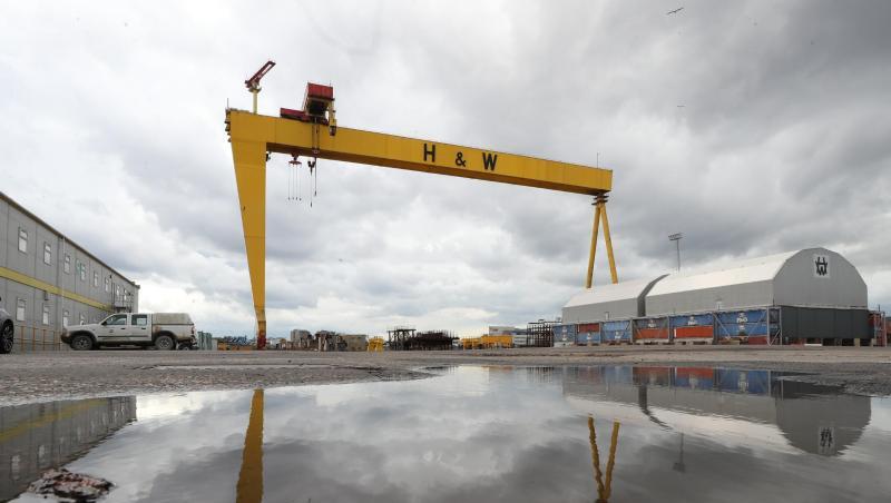 Ein Kran der Werft Harland & Wolff spiegelt sich auf dem Werksgelände in Belfast in einer Wasserlache. Ein Kran der Werft Harland & Wolff spiegelt sich auf dem Werksgelände in Belfast in einer Wasserlache.
