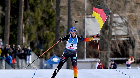 Franziska Preuß läuft mit der deutschen Fahne ins Ziel.