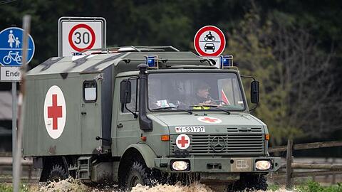Ein Sanitätsfahrzeug der Bundeswehr fährt über eine überflutete Straße.