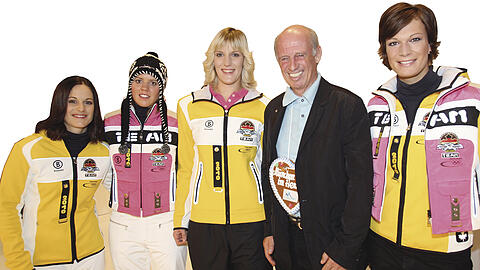 Rosa Zeiten: Willy Bogner mit seinen Ski-Models Viktoria Rebensburg (l.), Susanne Riesch und Maria Riesch (r.) im Olympia-Outfit für Vancouver. Foto: Minkoff/Augenklick