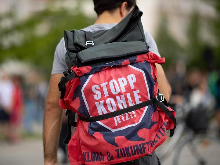 Ein Teilnehmer einer "Fridays for Future"-Klimademonstration hat an seinem Rucksack ein Transparent mit der Aufschrift "Stopp Kohle jetzt!" befestigt.