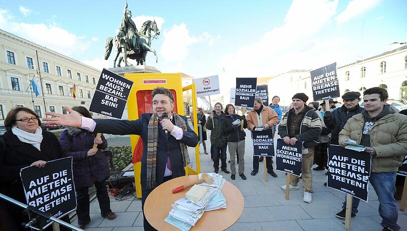 Mit der Versteigerung einer Telefonzelle als "Wohnraum" haben Aktivisten auf dem Odeonsplatz gegen die hohen Mieten in München demonstriert.